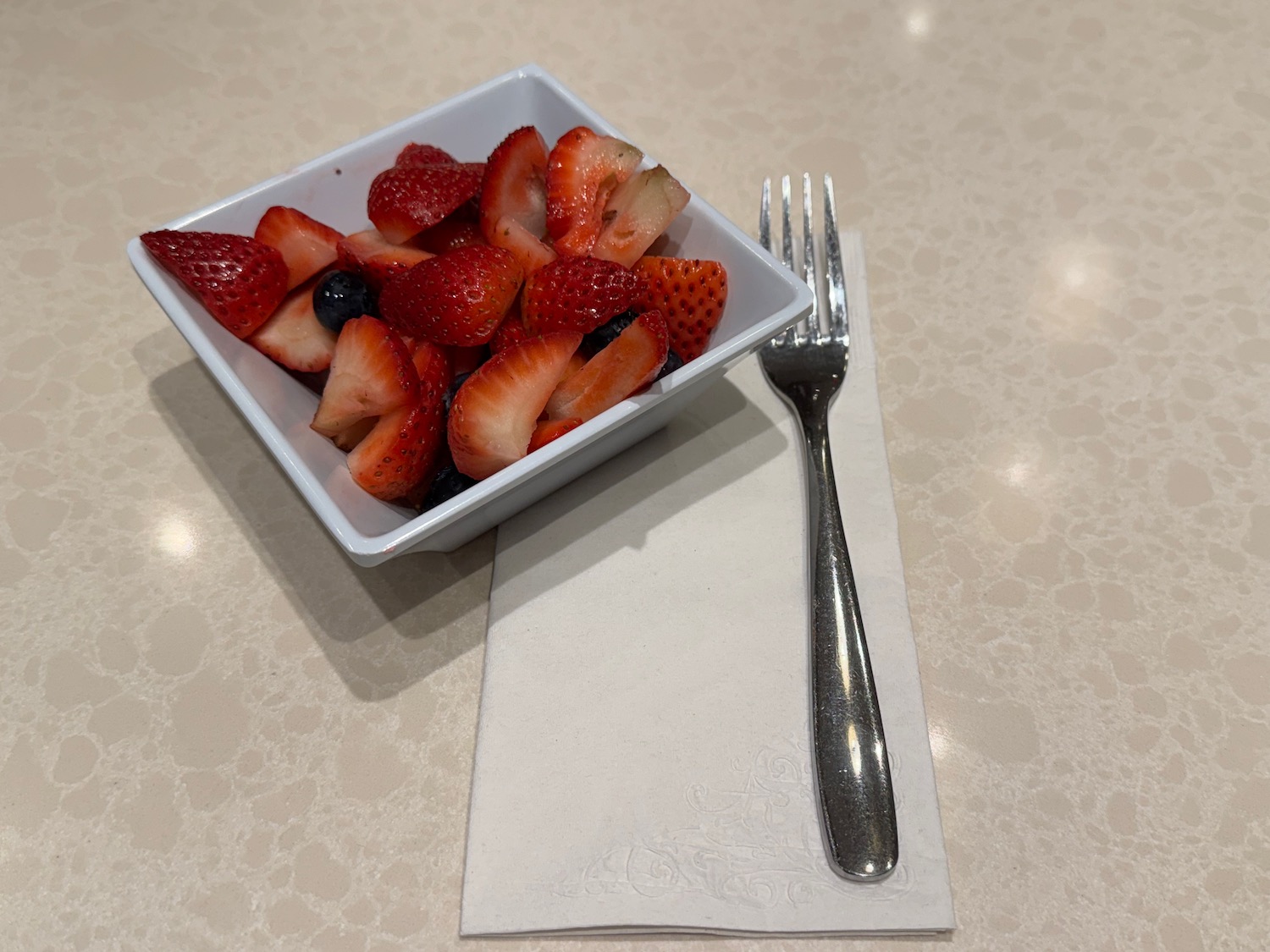 a bowl of strawberries and blueberries next to a fork