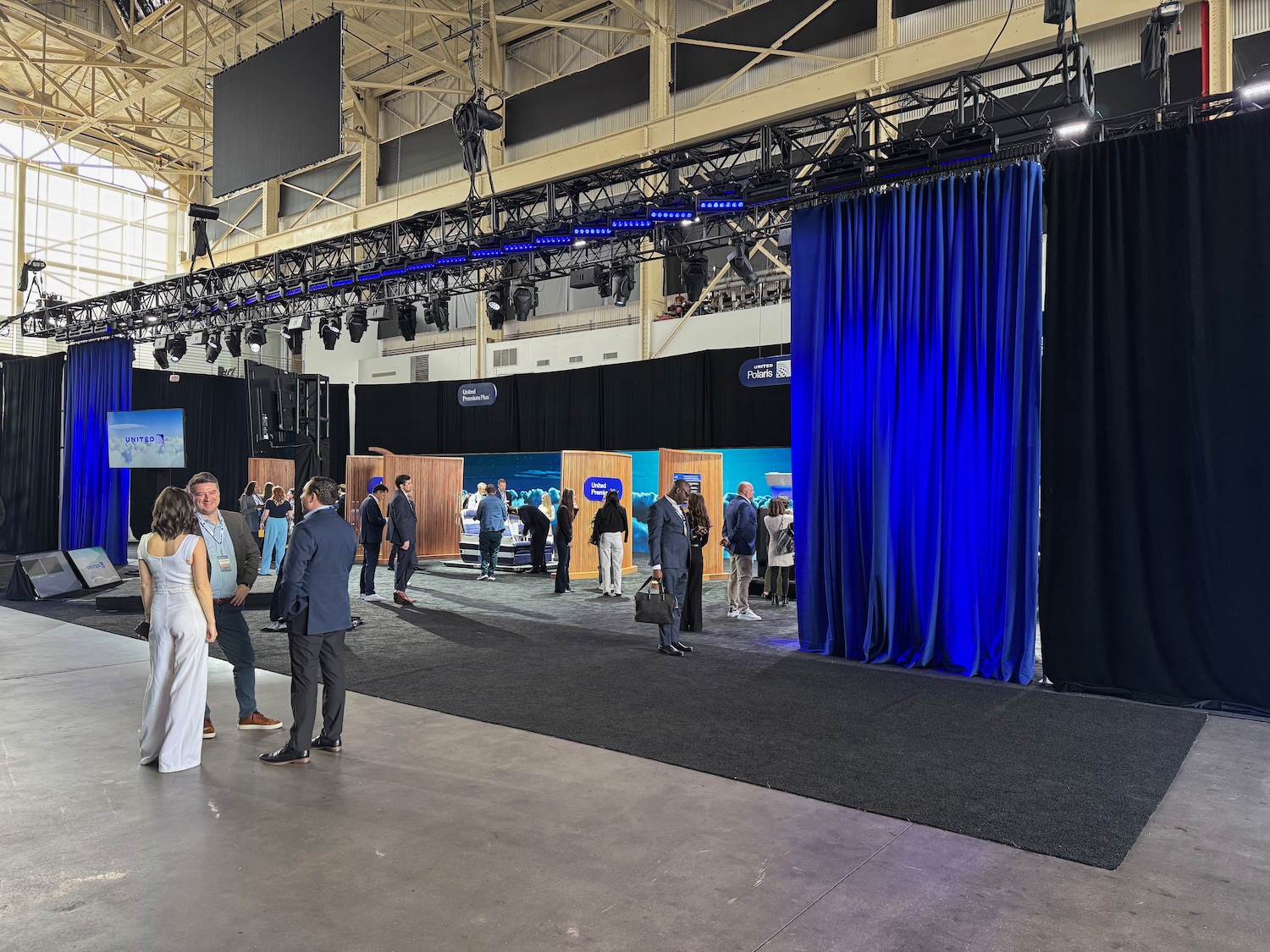 a group of people in a large room with blue curtains