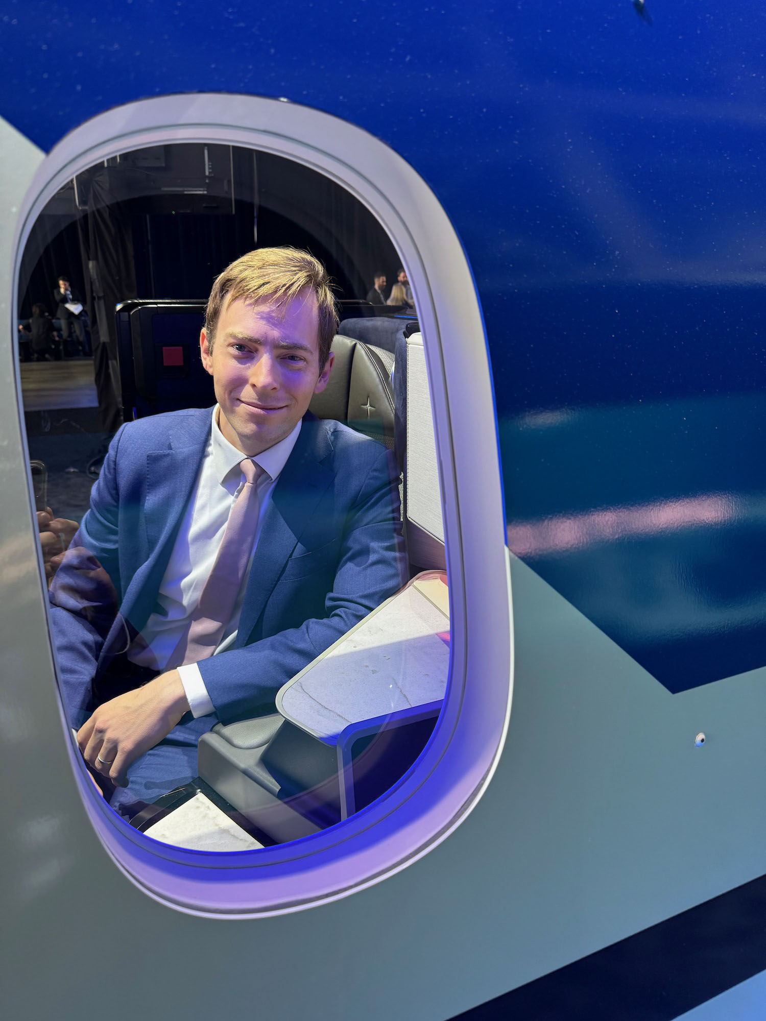 a man in a suit and tie sitting in a plane