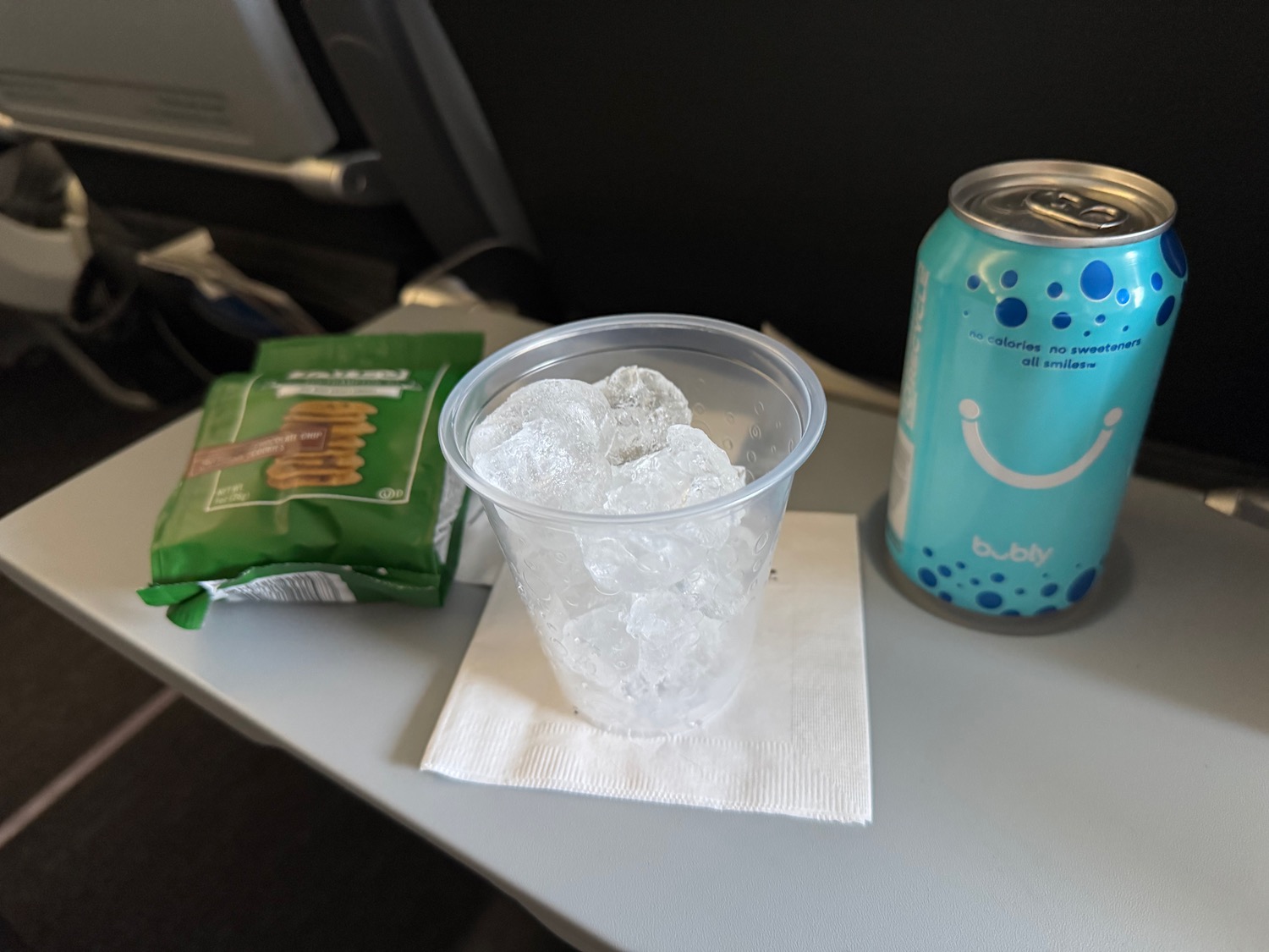 a plastic cup with ice and a can of soda on a table