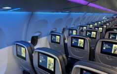 a row of seats with monitors on the side of the plane