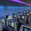 a row of seats with monitors on the side of the plane
