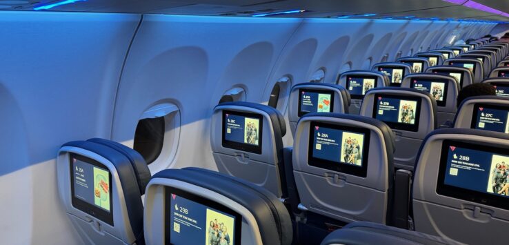 a row of seats with monitors on the side of the plane