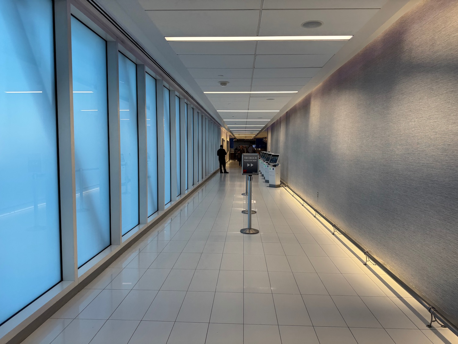 a long hallway with a man standing in front of a large window