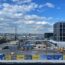 a construction site with a few buildings and a blue sky with clouds