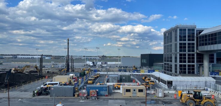 a construction site with a few buildings and a blue sky with clouds