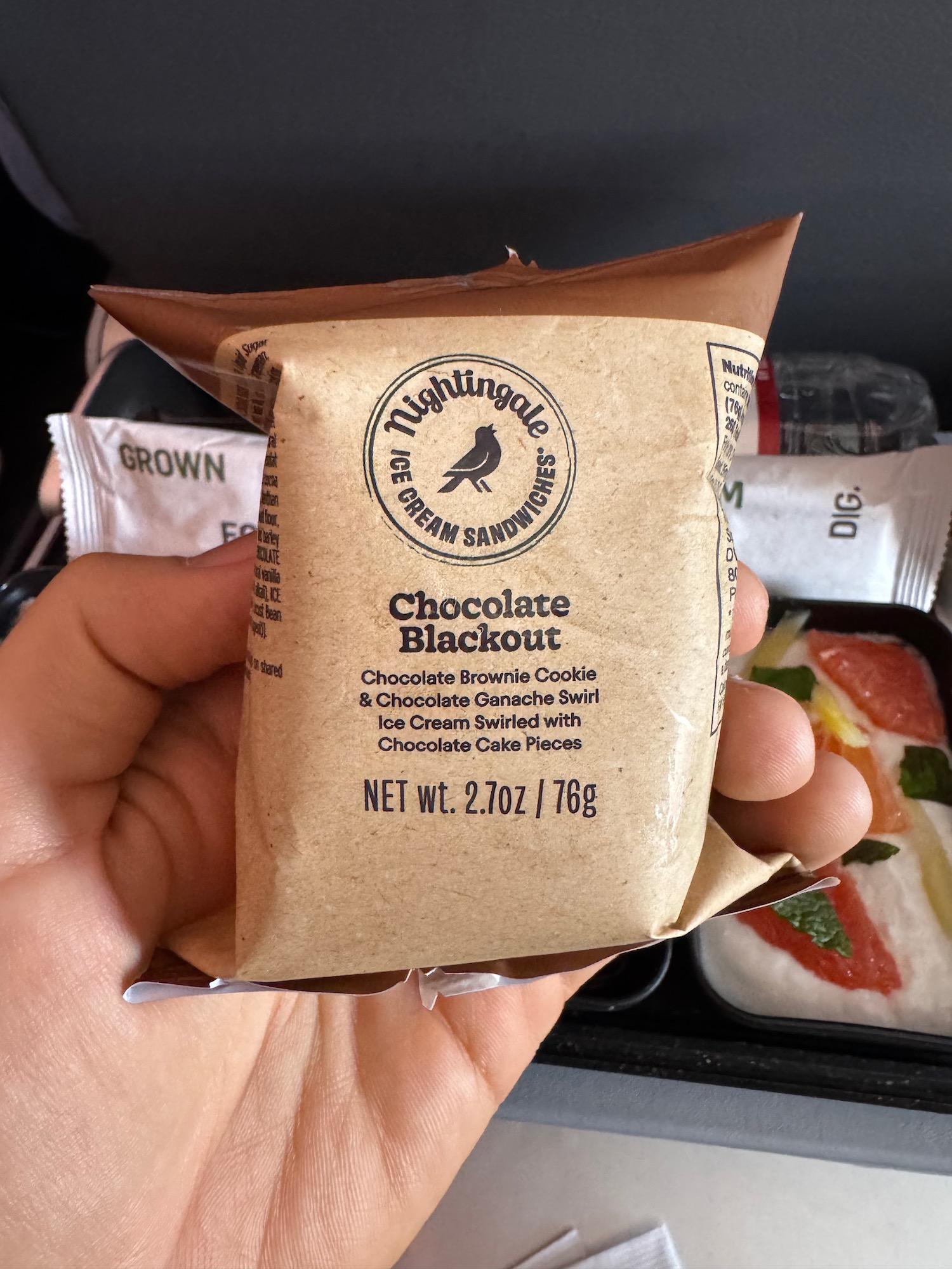 a hand holding a small brown bag of chocolate