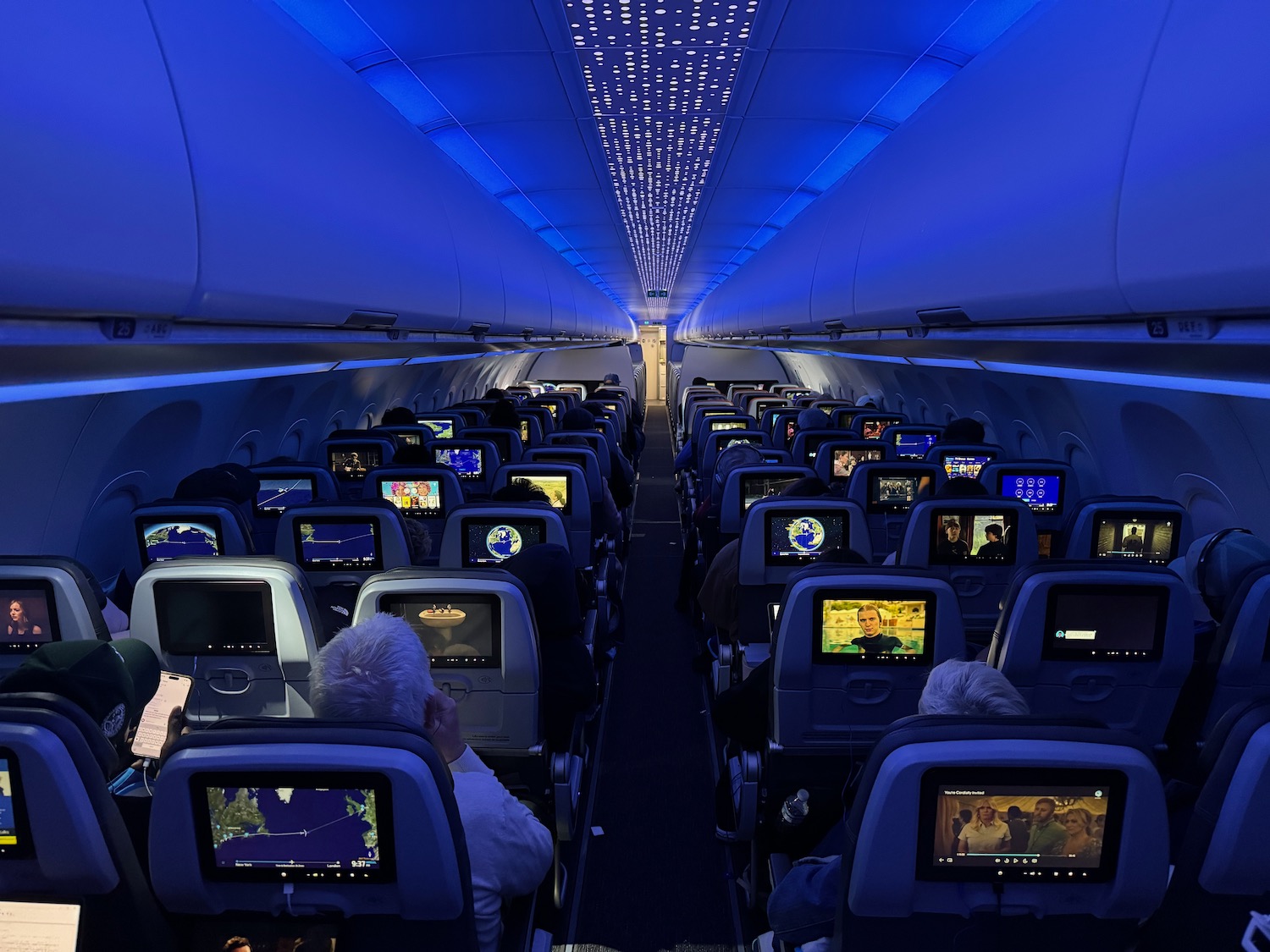 a group of people sitting in an airplane with monitors