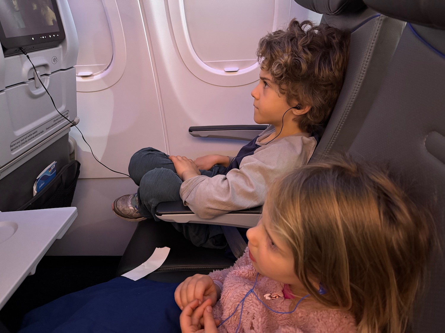a boy and girl sitting in an airplane