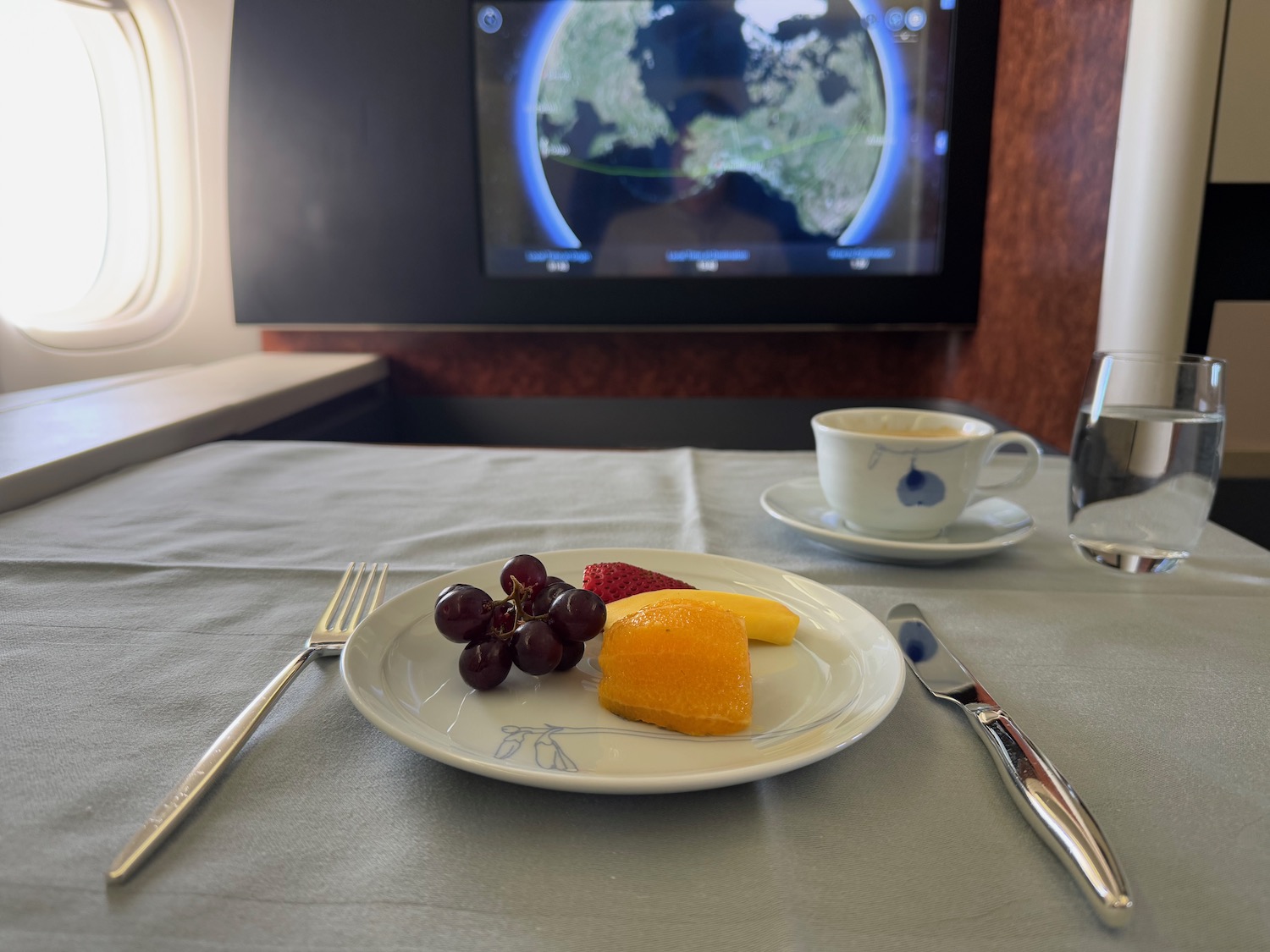 a plate of fruit and a cup of coffee on a table with a television in the background