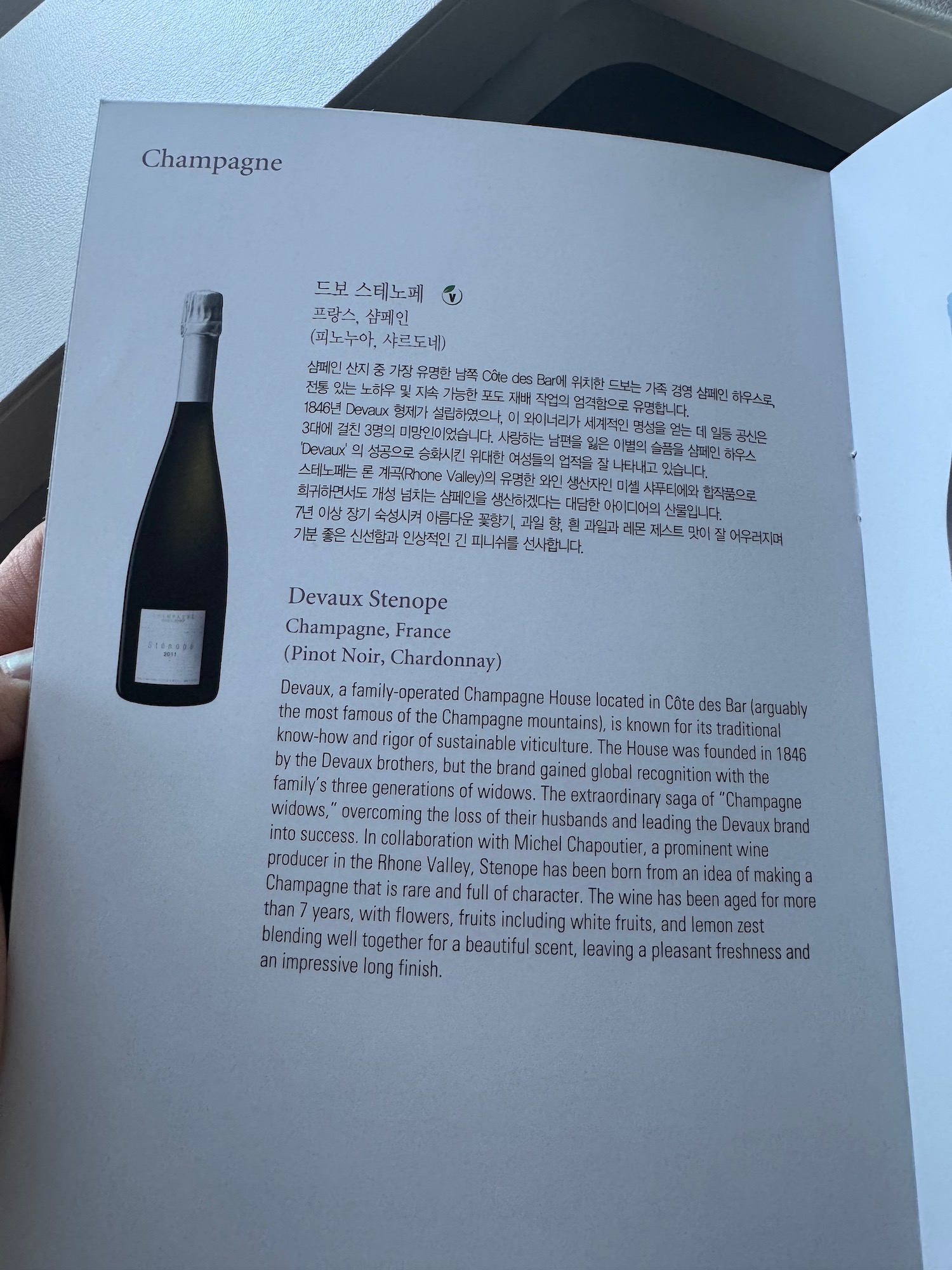 a hand holding a book with a bottle of champagne