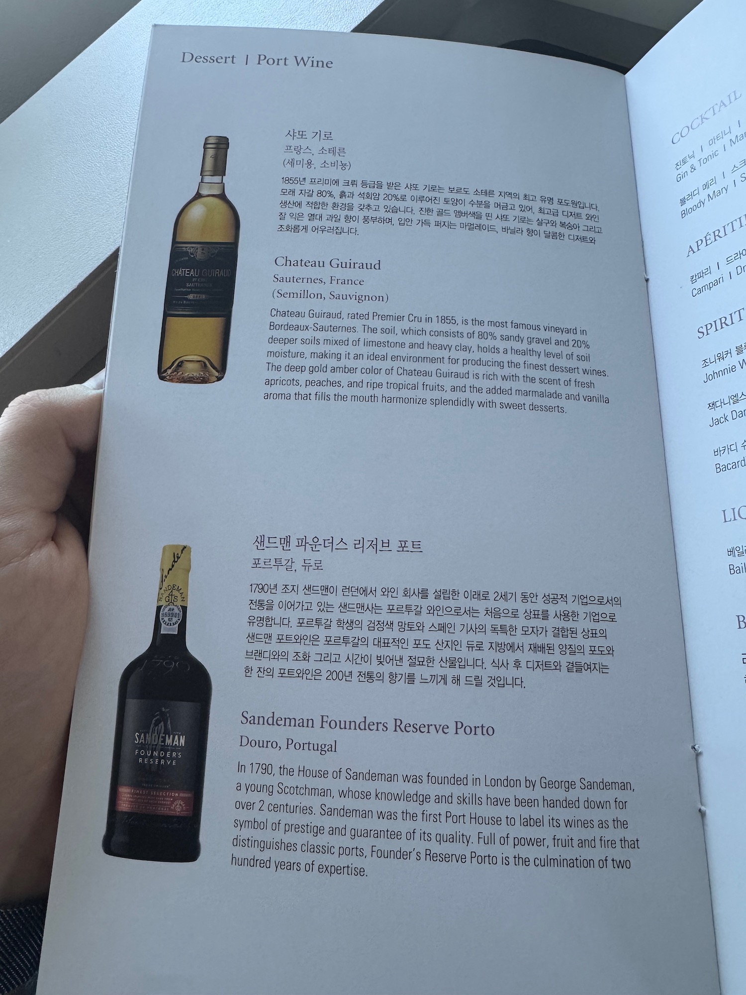 a hand holding a book with a picture of a bottle of wine