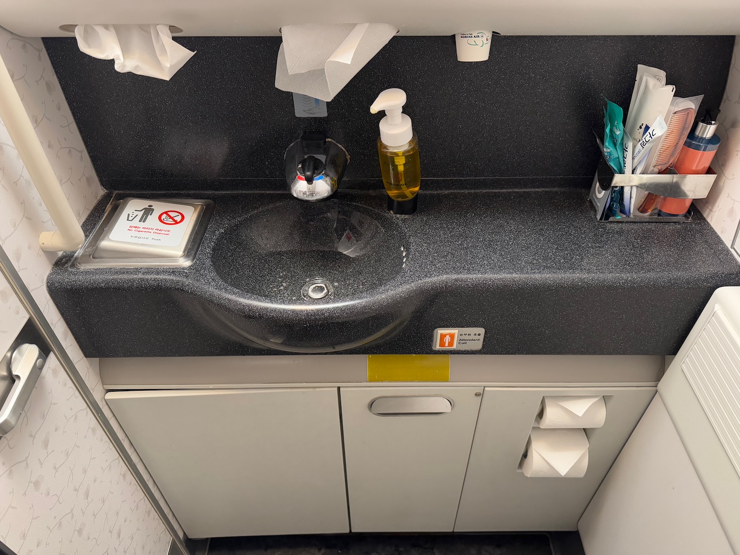 a sink with soap dispenser and toilet paper