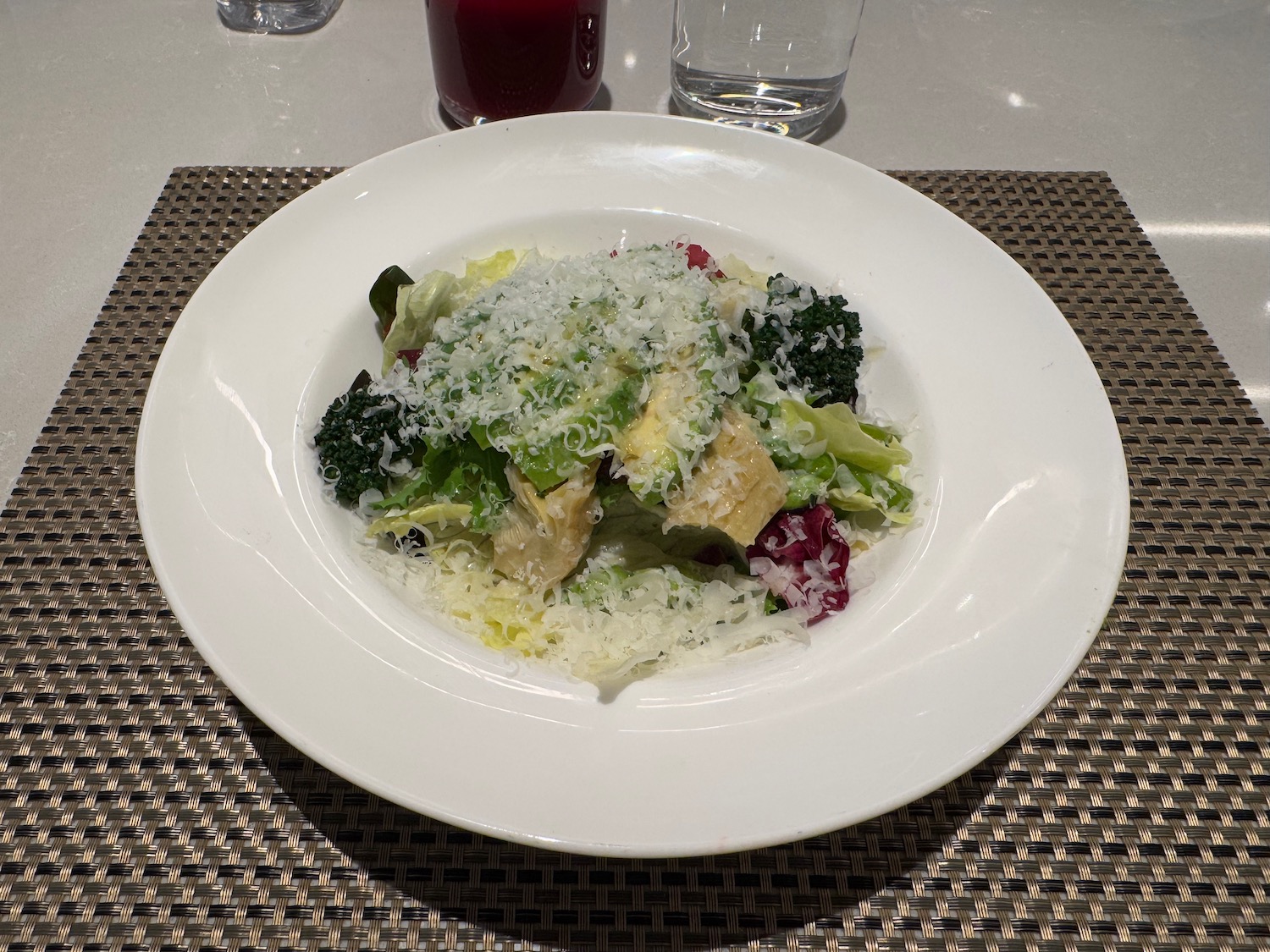 a plate of salad with cheese and broccoli