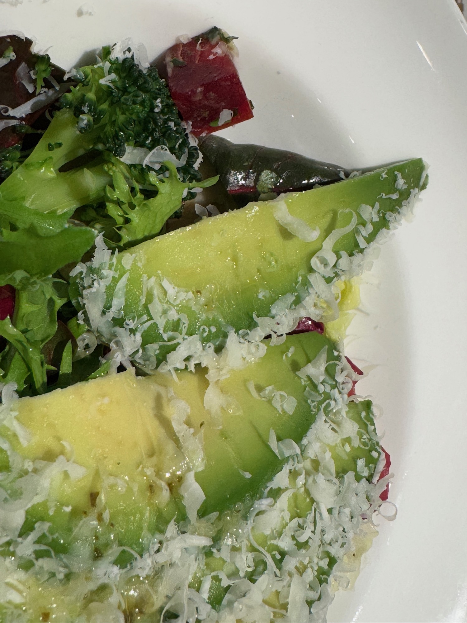a plate of salad with avocado and cheese