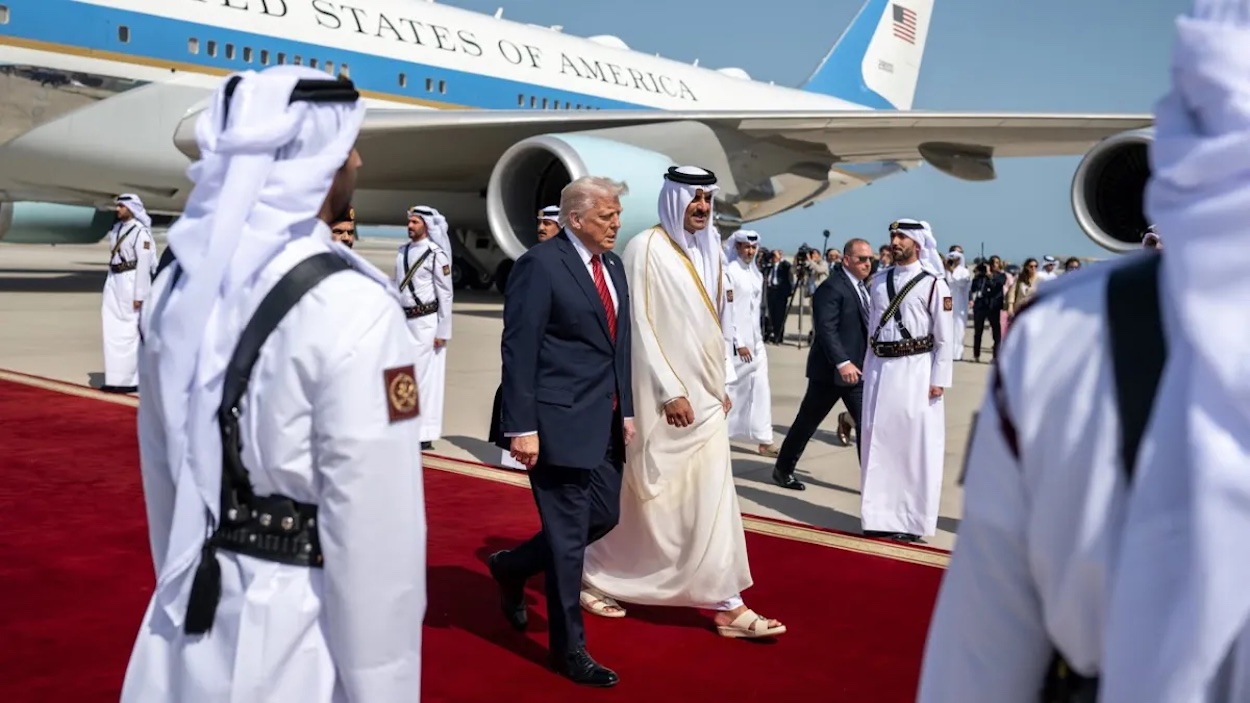 a man walking on a red carpet with a group of men in white robes