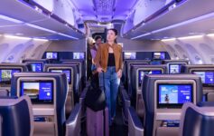 a woman walking in an airplane with a luggage