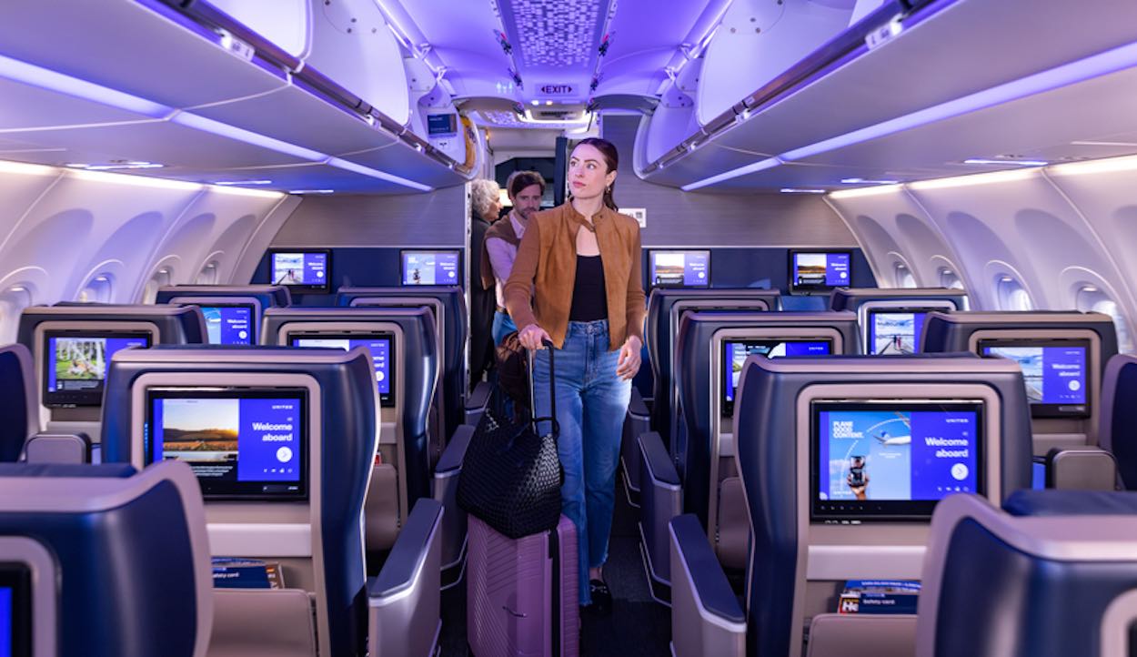 a woman walking in an airplane with a luggage