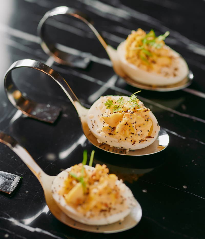 spoons with hard boiled eggs on a black surface