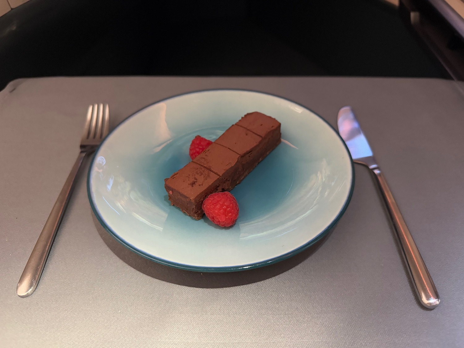 a plate with a piece of chocolate cake and raspberries on it