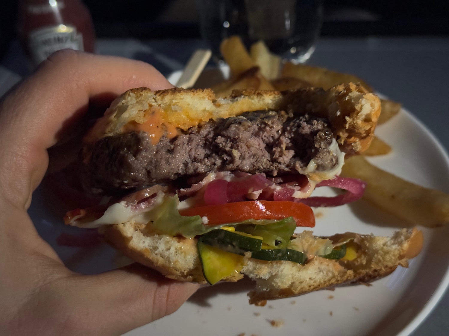 a hand holding a burger with fries