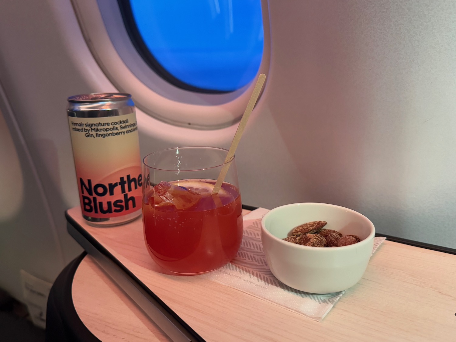 a drink and a bowl of nuts on a table