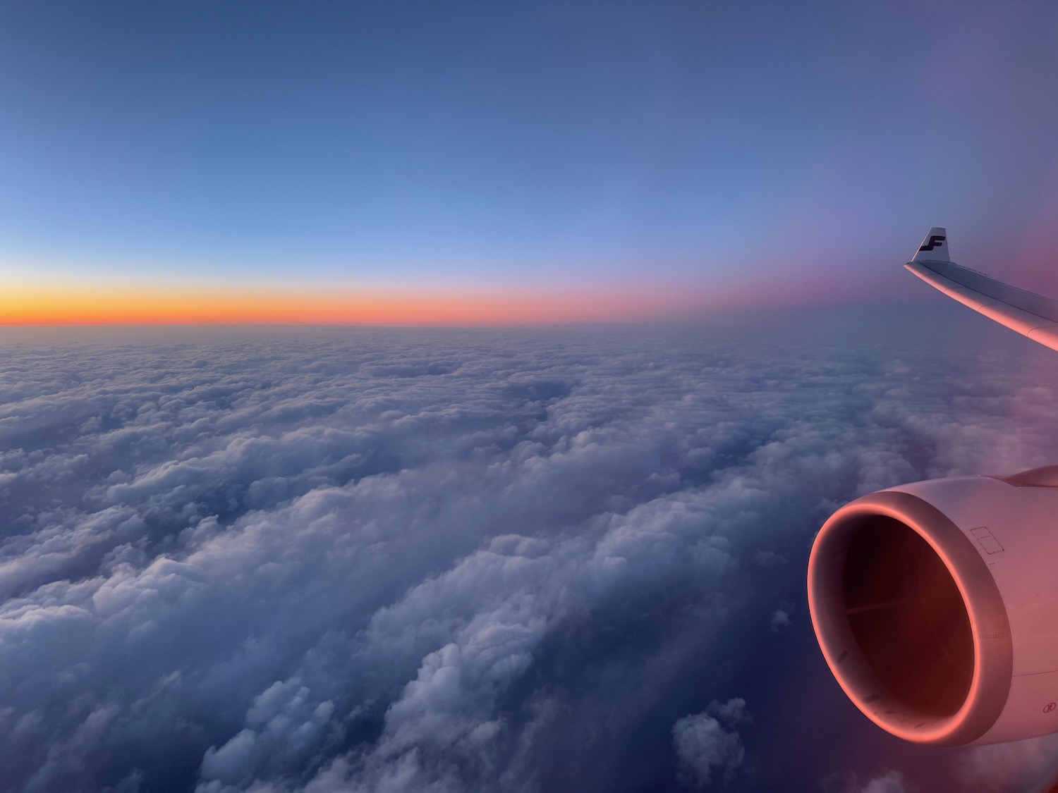 an airplane wing with clouds in the background