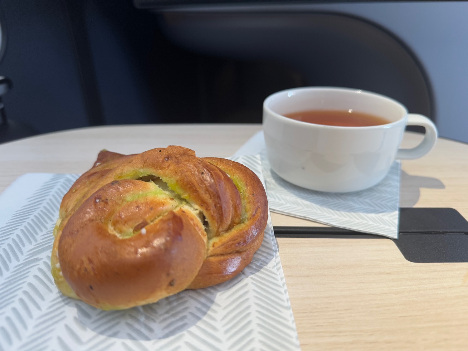 a roll on a napkin next to a cup of tea
