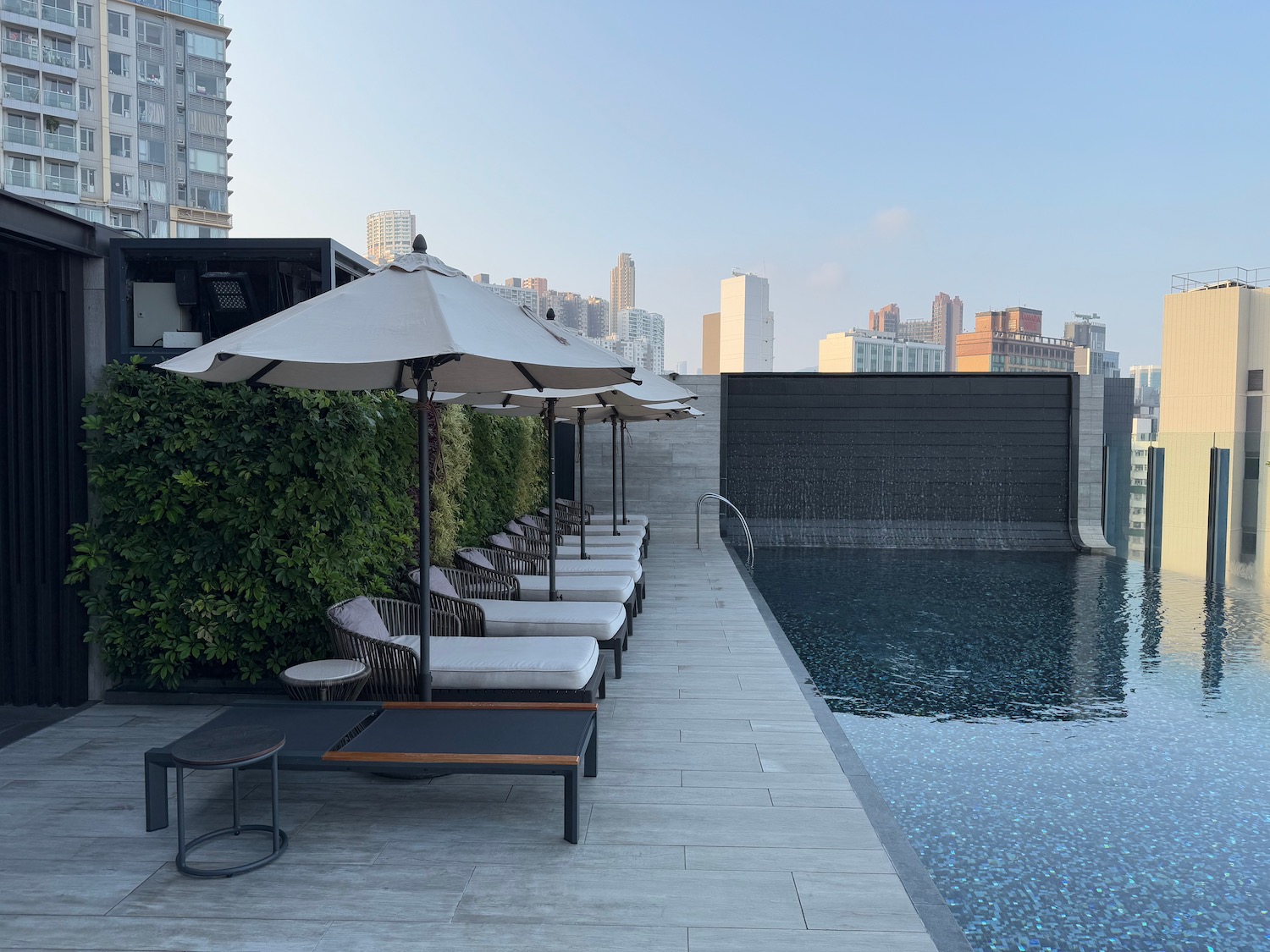 a pool with chairs and umbrellas by a building