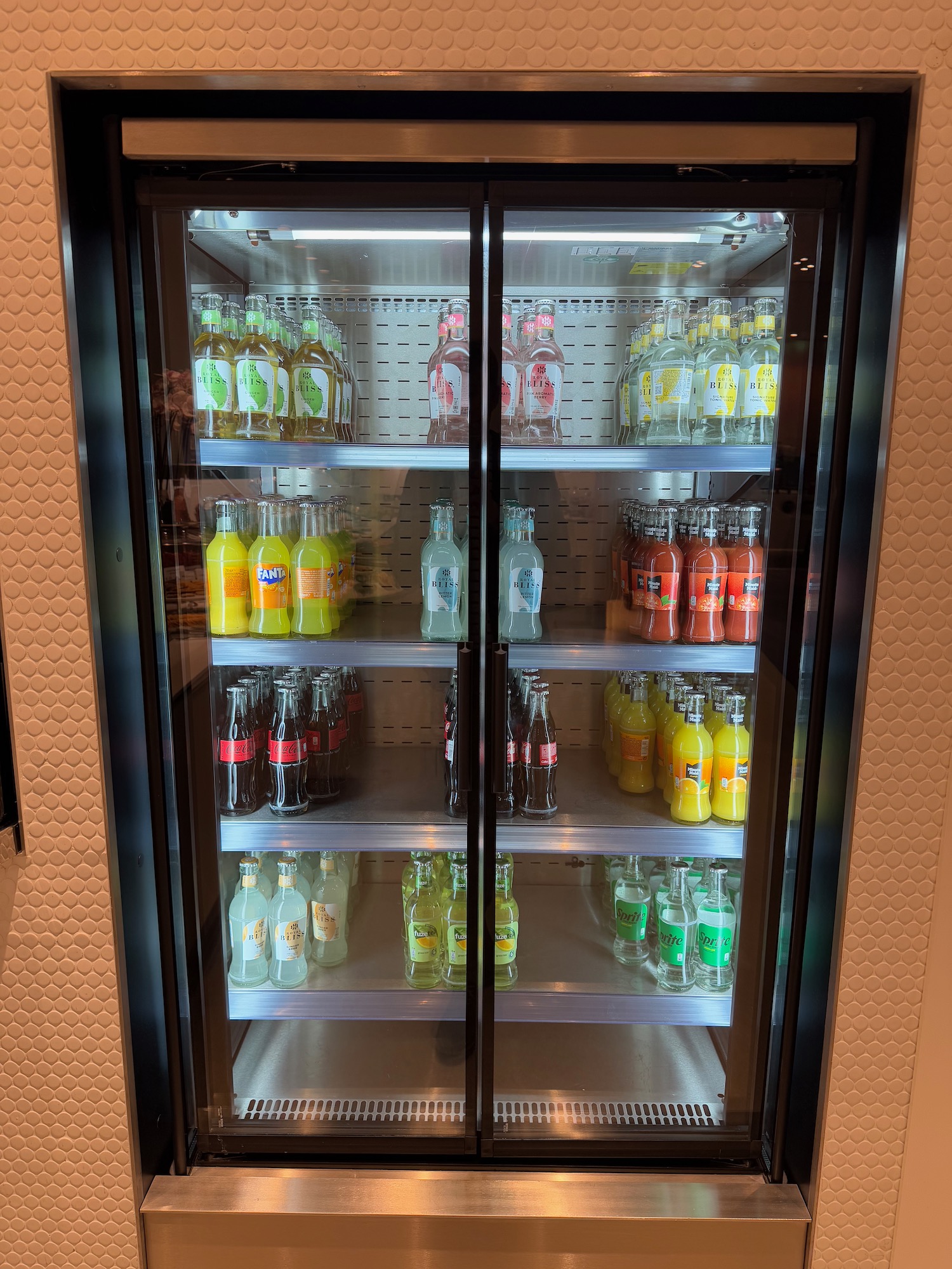 a glass door refrigerator with bottles of soda