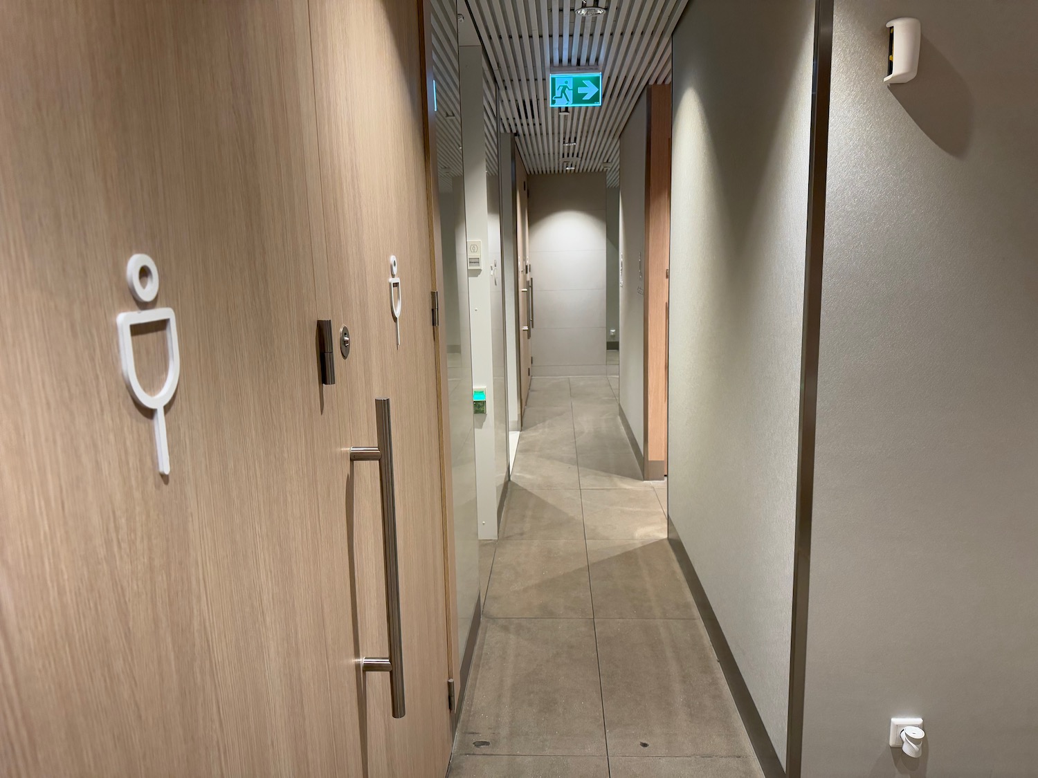 a hallway with doors and a green sign