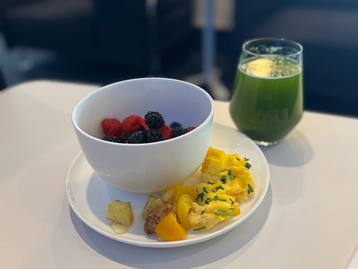 a bowl of fruit and scrambled eggs on a plate next to a drink