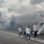 people walking on a runway with a plane in the background