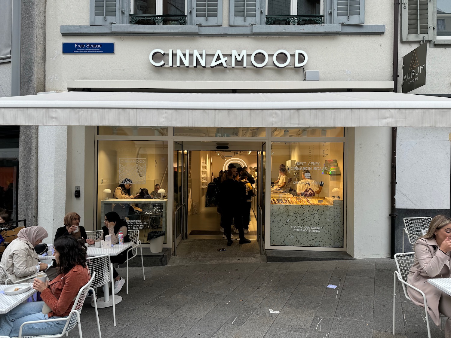 a store front with people sitting at tables outside