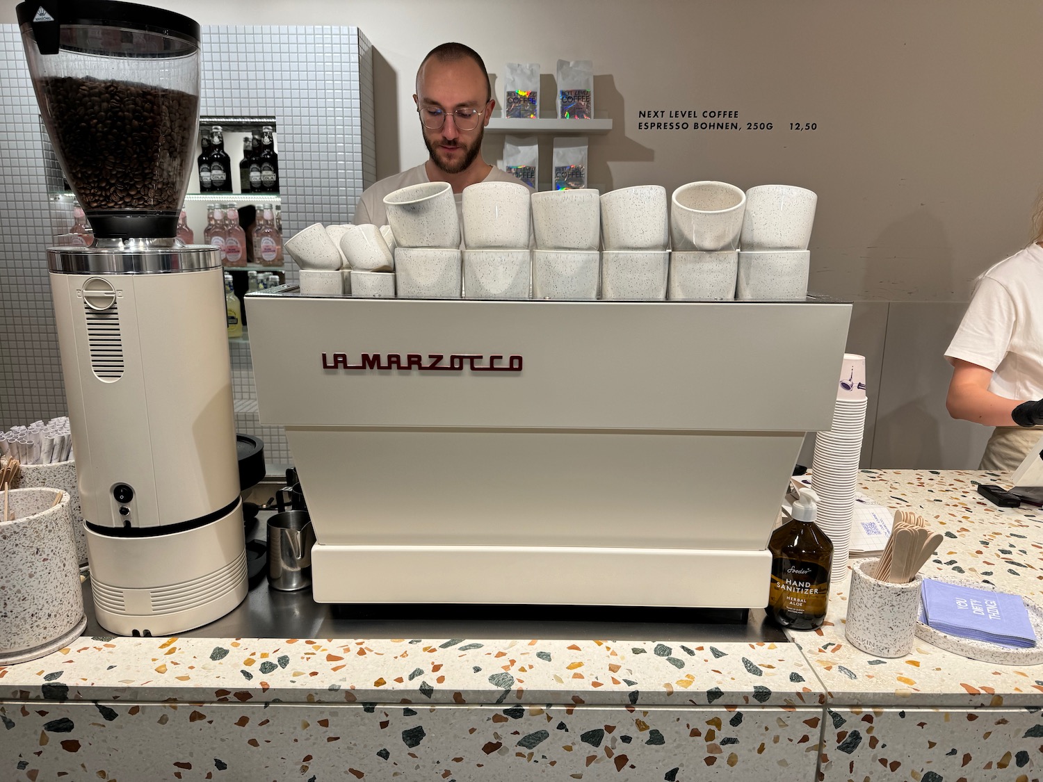 a man standing behind a counter with a coffee machine
