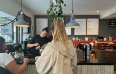 a woman standing at a counter in a coffee shop