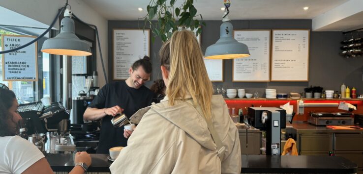 a woman standing at a counter in a coffee shop