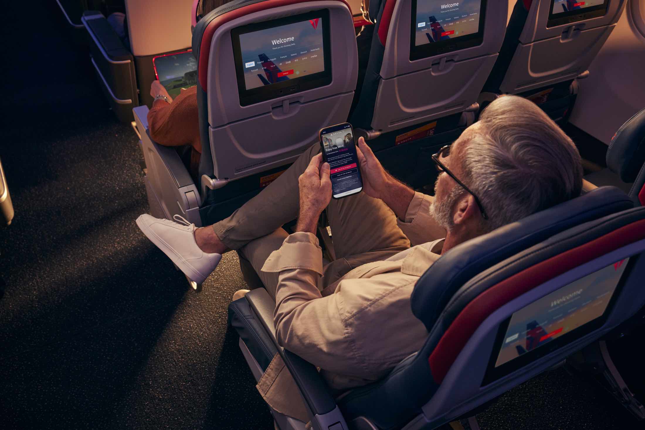 a man sitting in an airplane with his phone