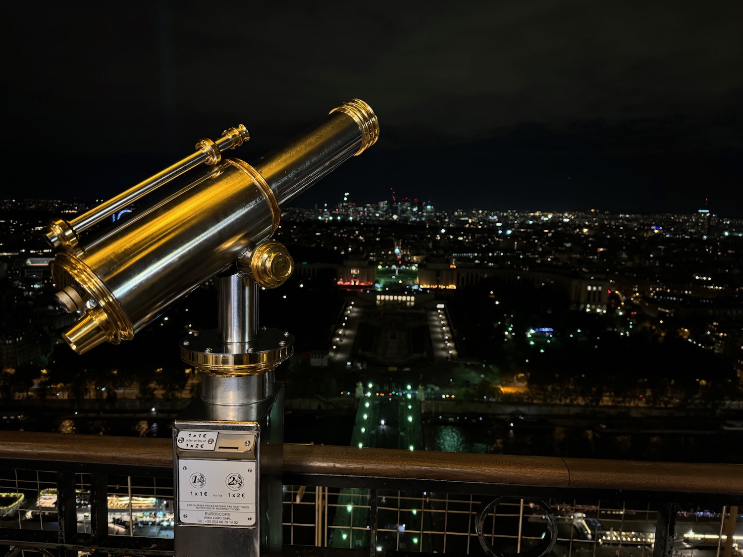 a telescope on a railing overlooking a city