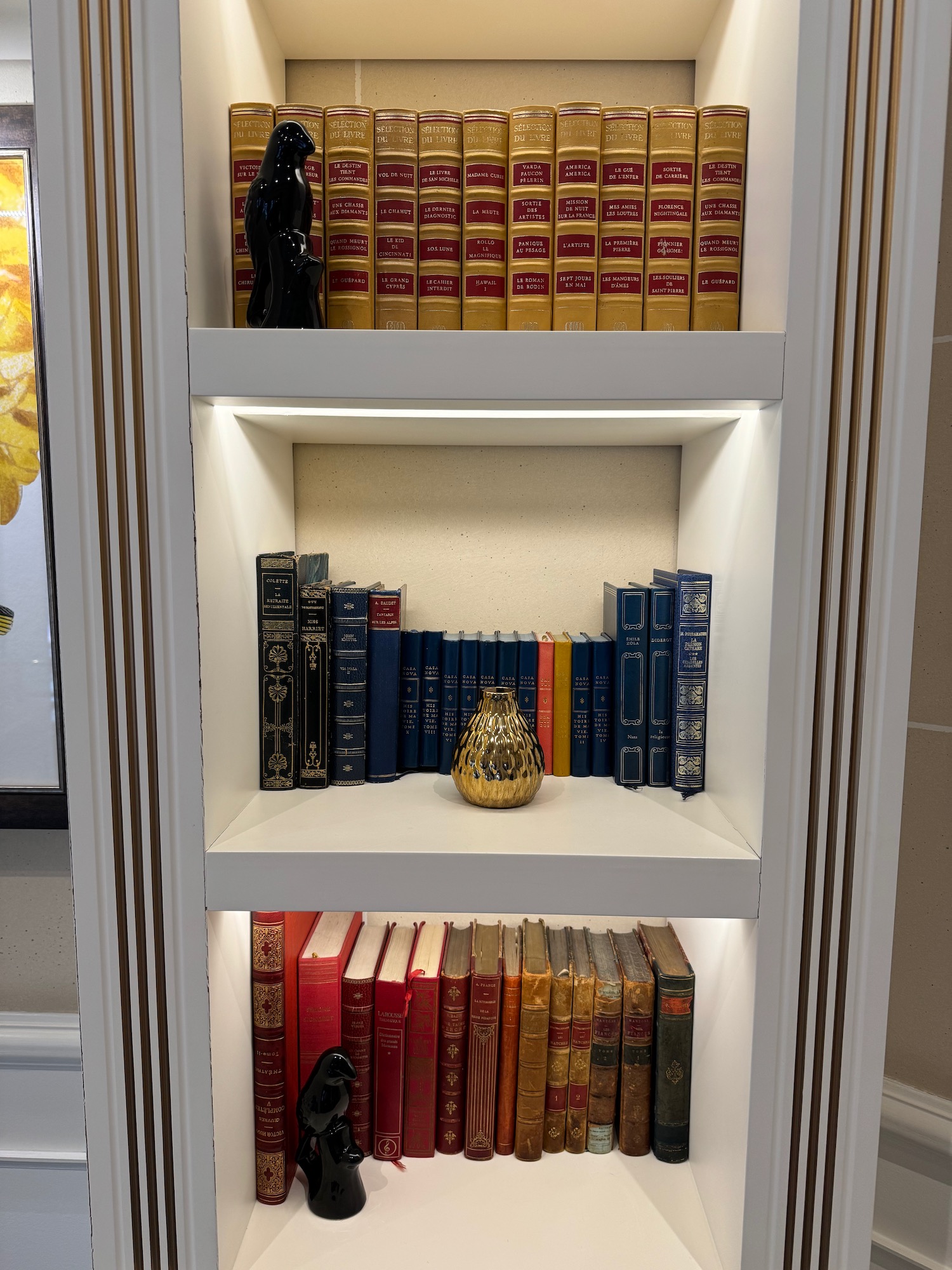 a shelf with books and a statue of a bird