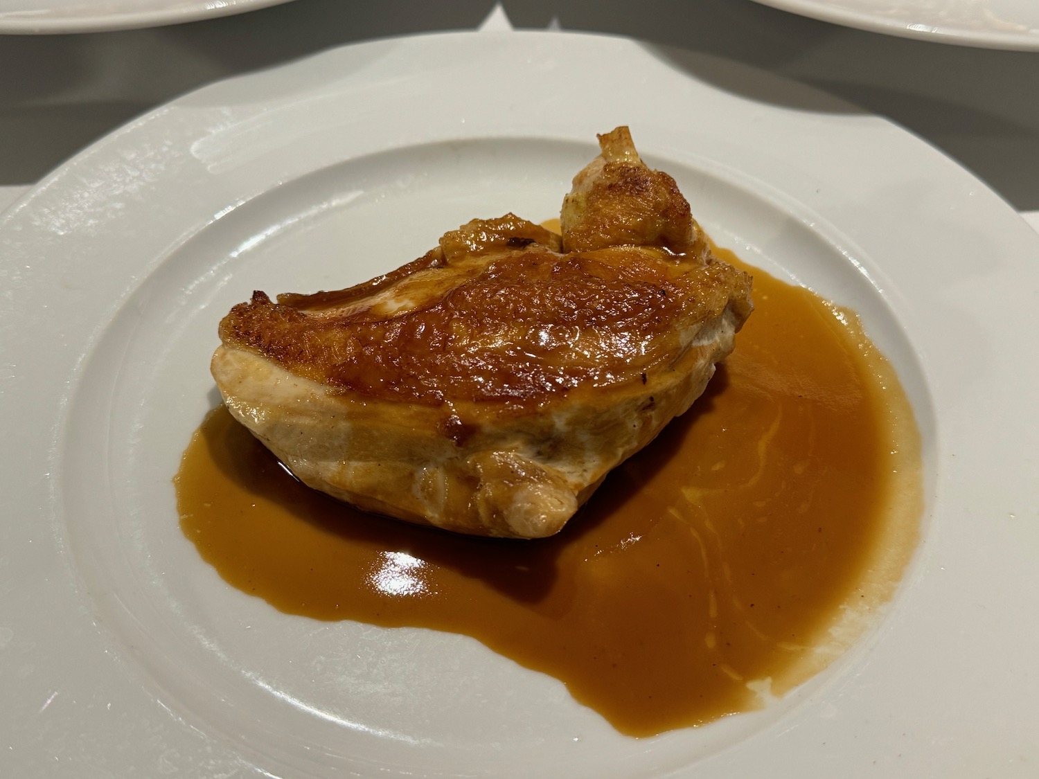 a piece of meat with brown sauce on a white plate