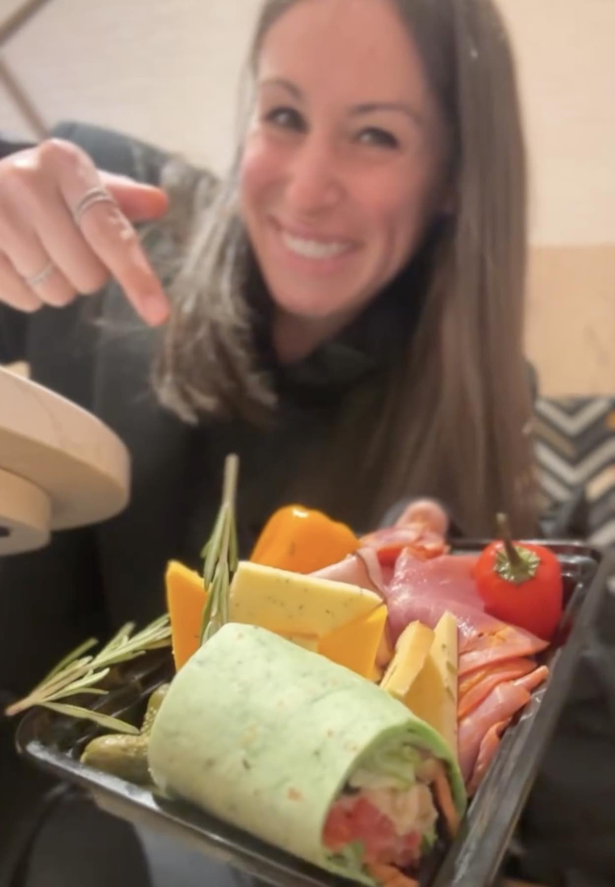 a woman pointing at a platter of food