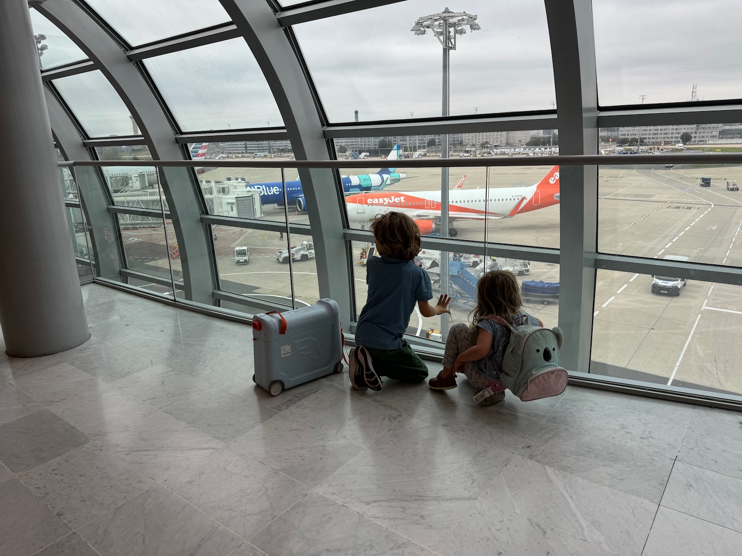 a boy and girl looking out a window at an airplane