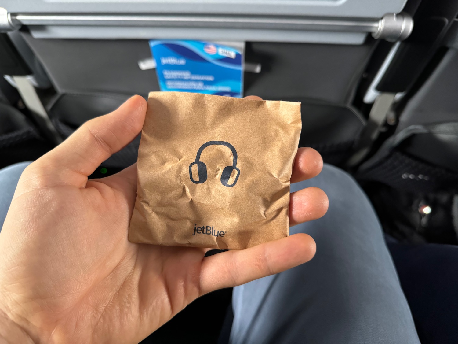 a hand holding a brown paper bag with headphones on it