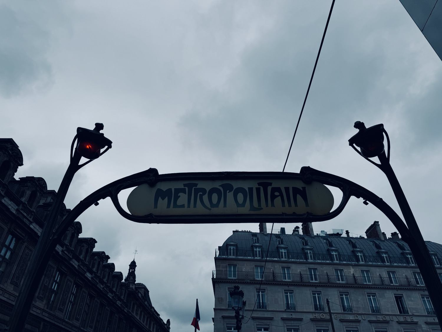 a sign with a street light and buildings in the background