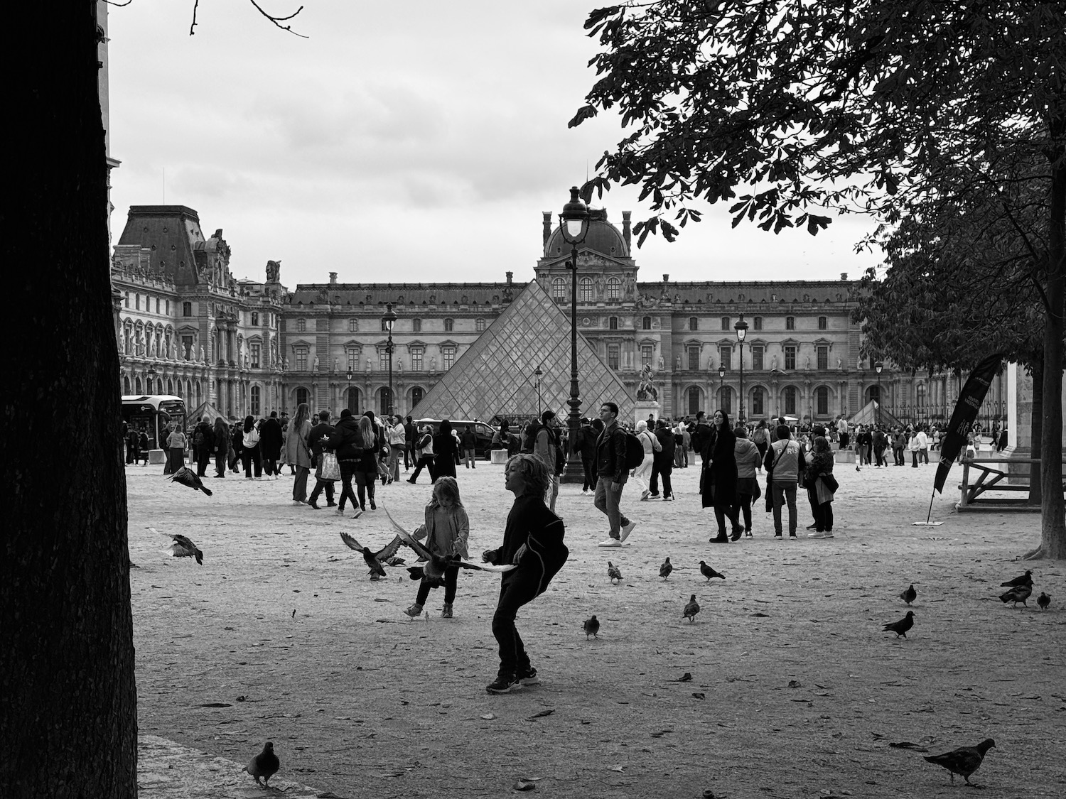 a group of people in a courtyard with a pyramid and a building