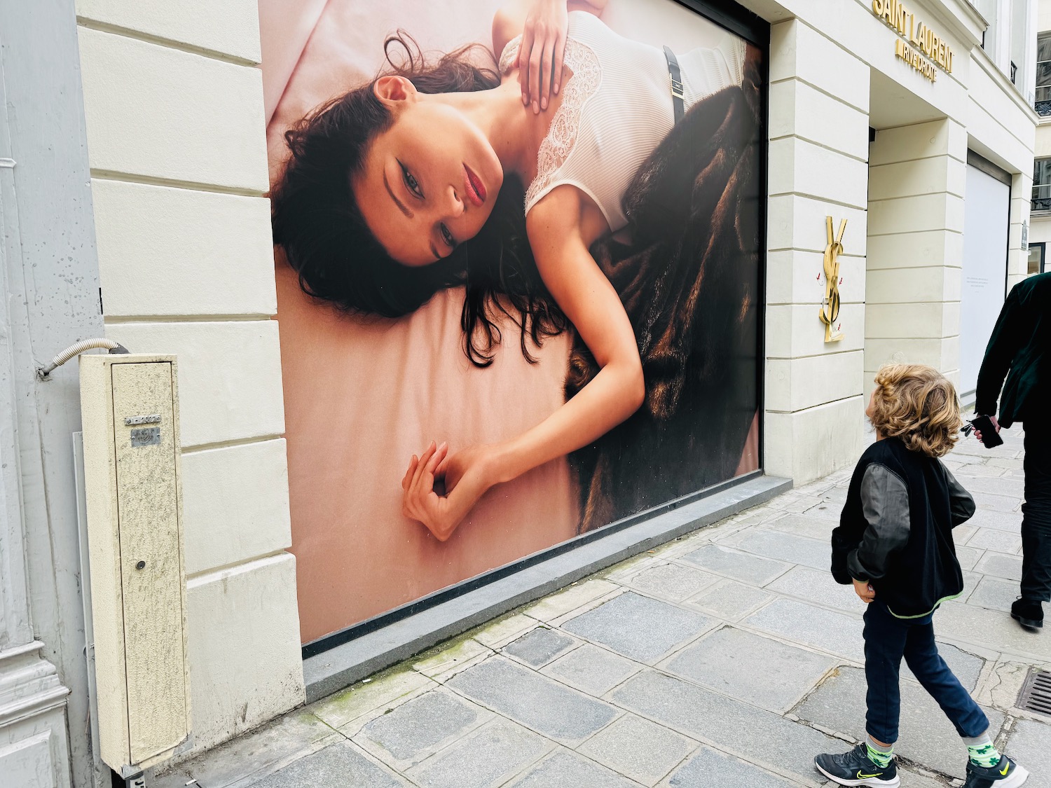 a person standing on a sidewalk looking at a poster of a woman