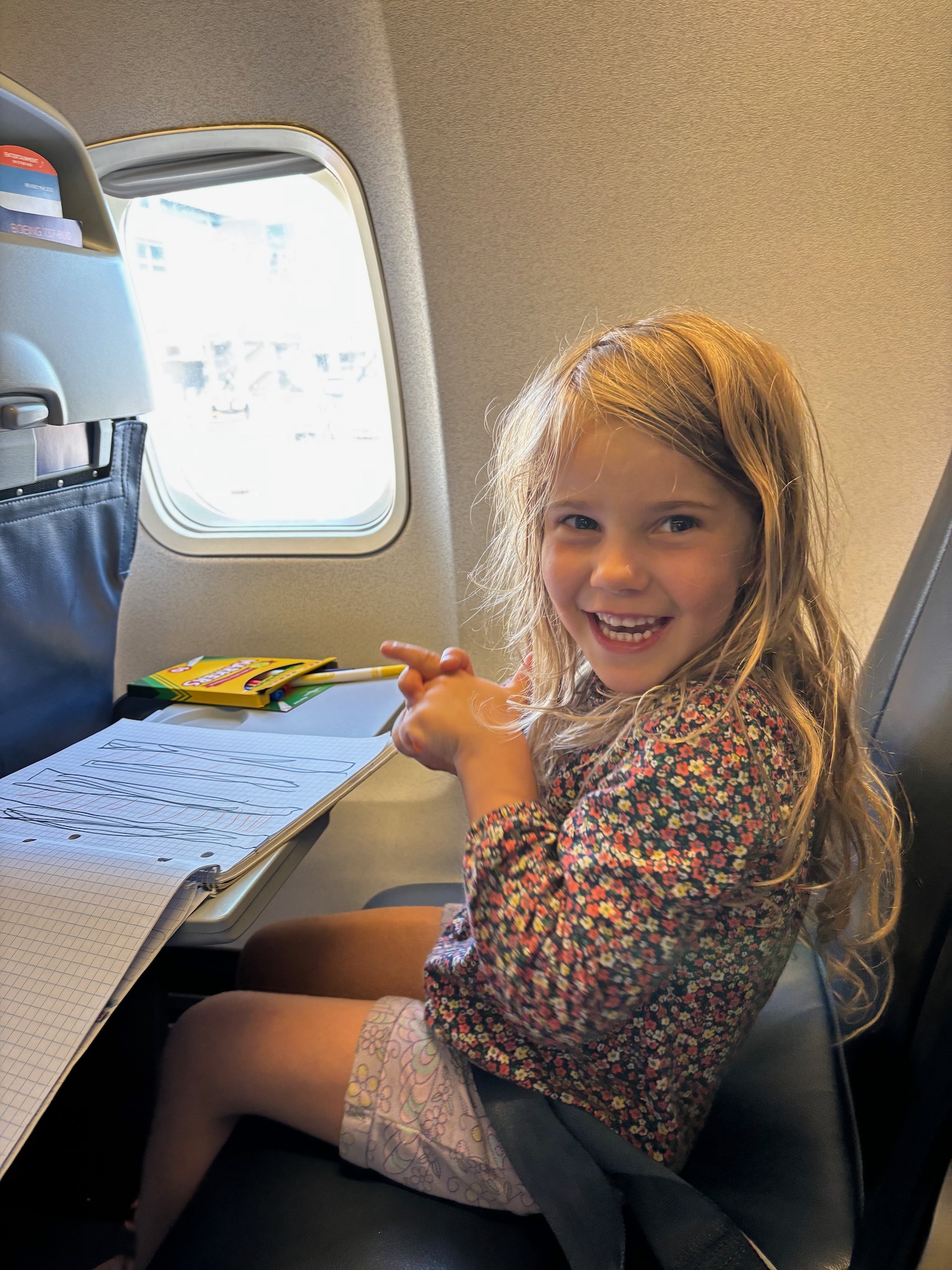 a girl sitting in a chair pointing at a piece of paper