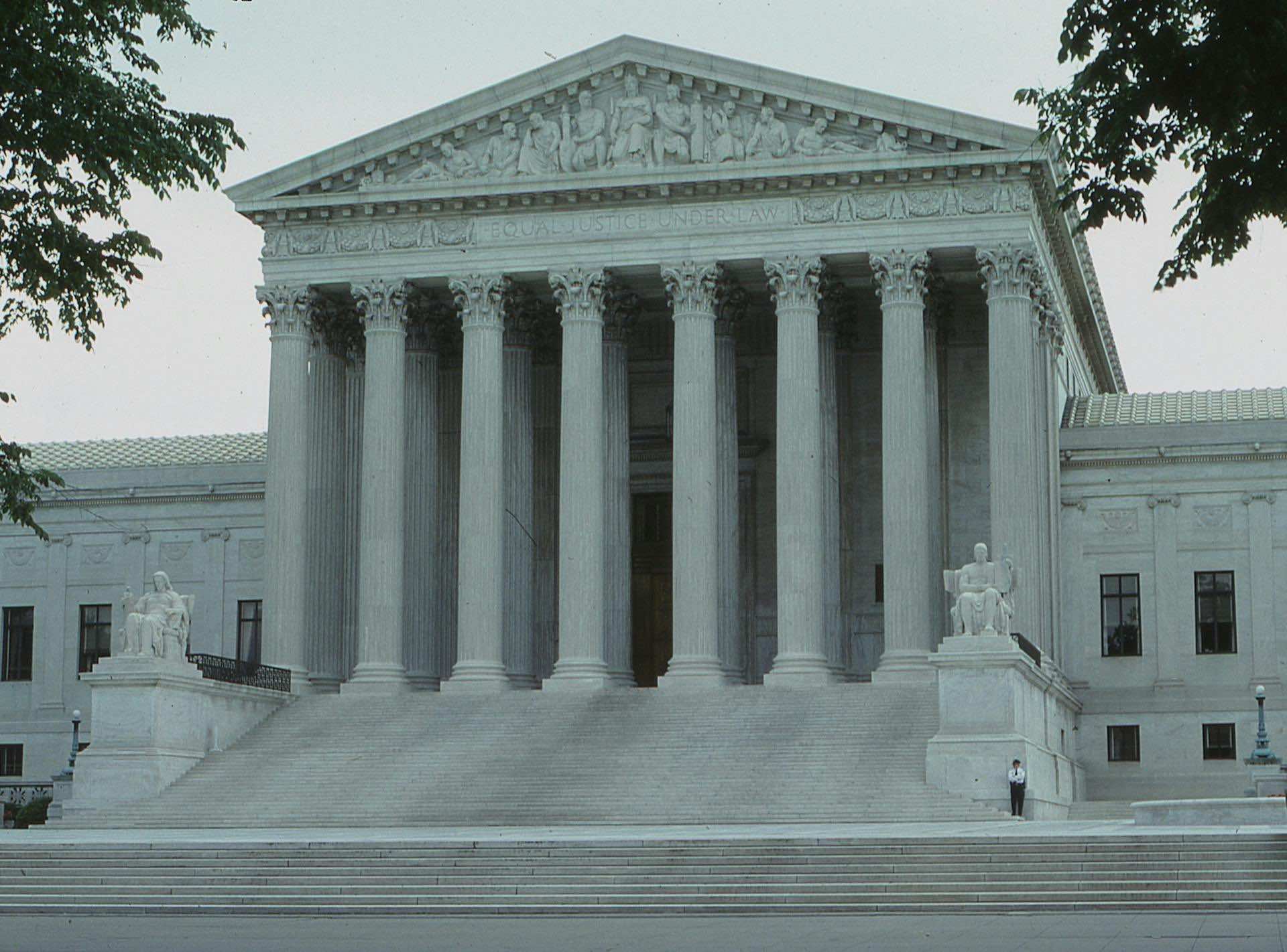 a white building with columns with United States Supreme Court Building in the background