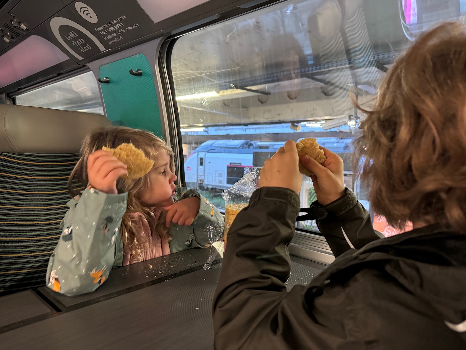 a woman and a girl eating food on a train